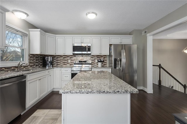 kitchen featuring tasteful backsplash, visible vents, appliances with stainless steel finishes, a sink, and a kitchen island