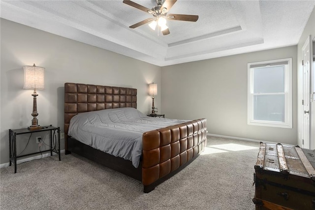 bedroom featuring a tray ceiling, baseboards, and carpet