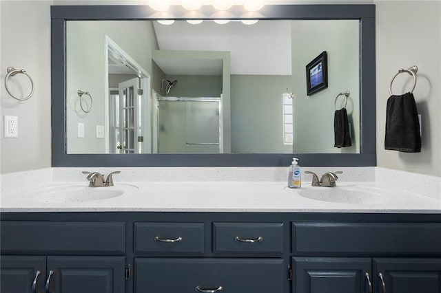 bathroom with double vanity, a stall shower, and a sink