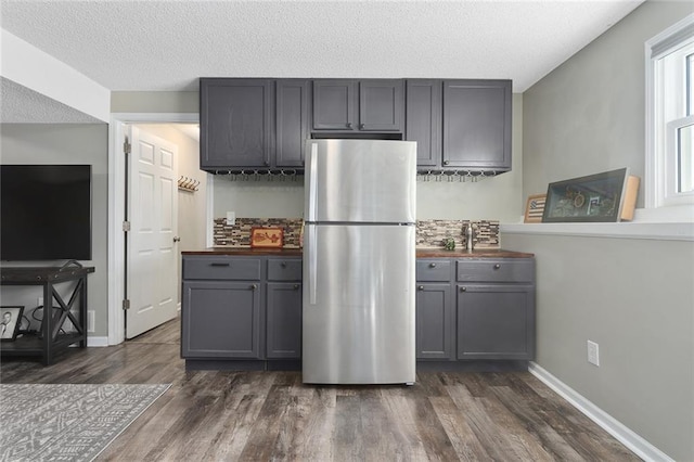 kitchen featuring butcher block counters, gray cabinets, dark wood finished floors, and freestanding refrigerator