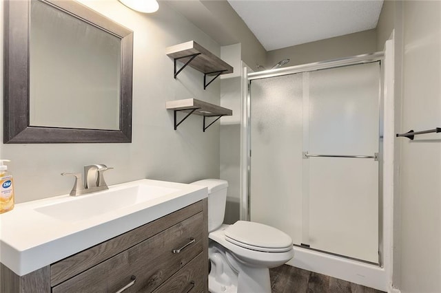 full bathroom featuring toilet, a stall shower, wood finished floors, and vanity