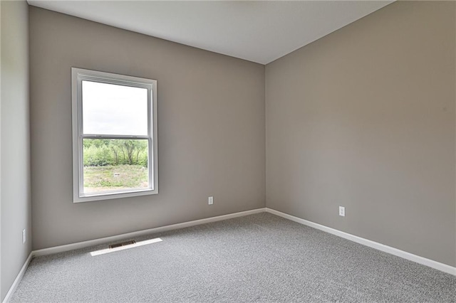 empty room with carpet flooring, visible vents, and baseboards