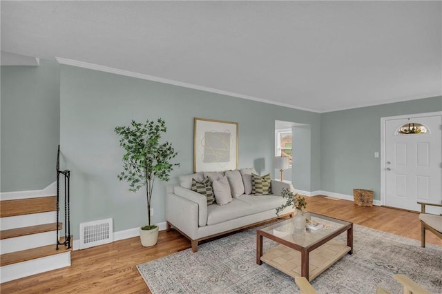 living room with wood finished floors, visible vents, baseboards, stairway, and crown molding