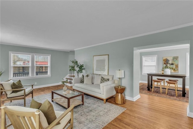 living area featuring baseboards, crown molding, and light wood finished floors