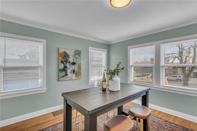 dining space featuring ornamental molding, wood finished floors, and baseboards