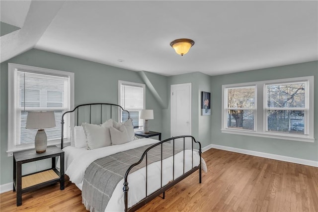 bedroom featuring lofted ceiling, light wood-style flooring, and baseboards