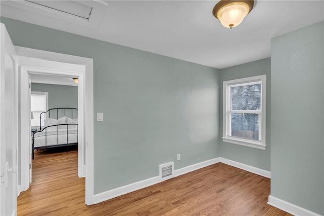 spare room featuring visible vents, baseboards, and wood finished floors