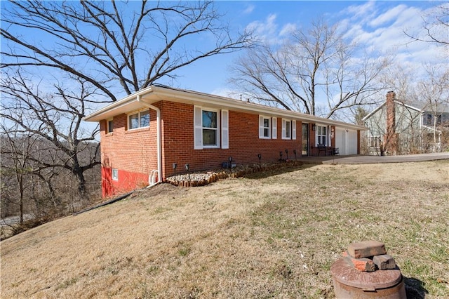 view of front facade with driveway, brick siding, and a front yard