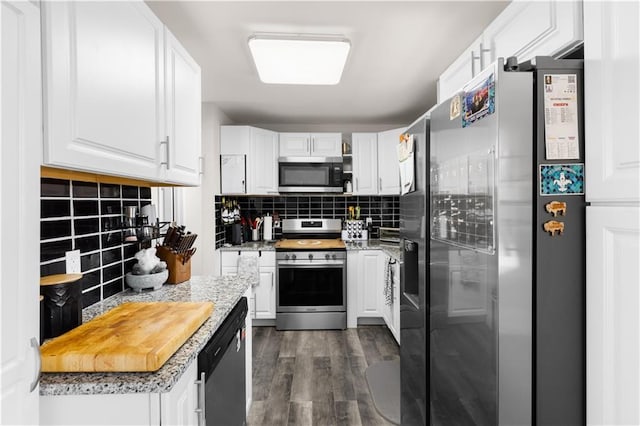 kitchen with white cabinetry, decorative backsplash, dark wood finished floors, and stainless steel appliances