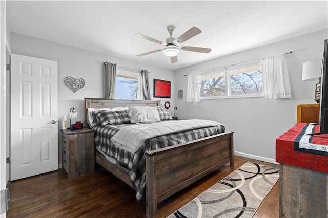 bedroom featuring dark wood finished floors, multiple windows, baseboards, and ceiling fan