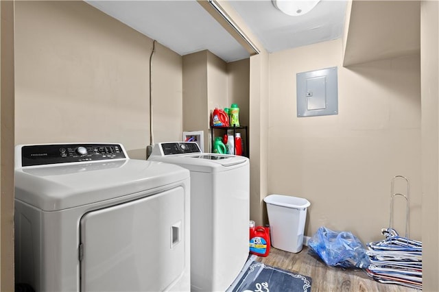 washroom featuring washer and clothes dryer, laundry area, electric panel, and wood finished floors