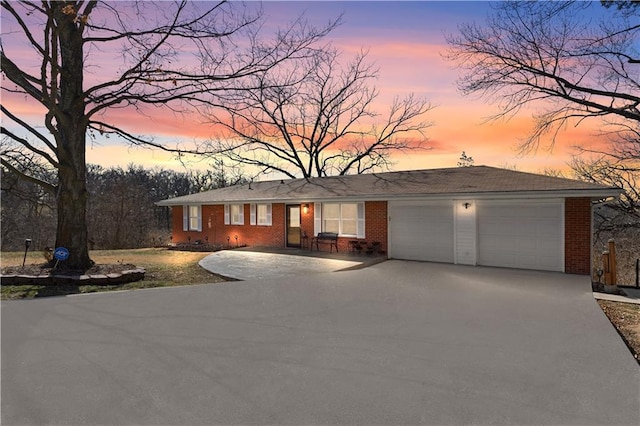 ranch-style home with an attached garage, brick siding, and driveway