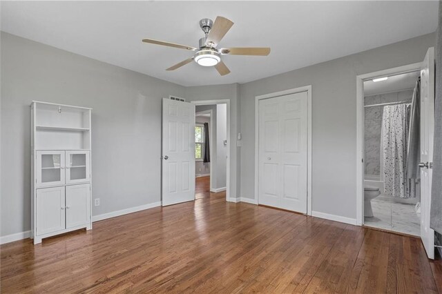 904 E Golf Hill Dr, Excelsior Springs, MO 64024 - unfurnished bedroom with wood finished floors, baseboards, and ensuite bath