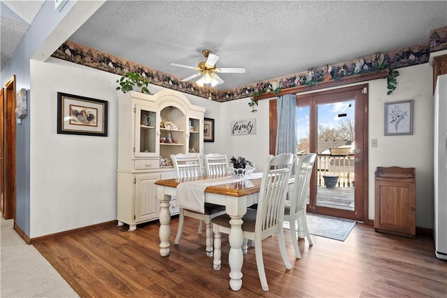 dining space with a ceiling fan, a textured ceiling, baseboards, and wood finished floors