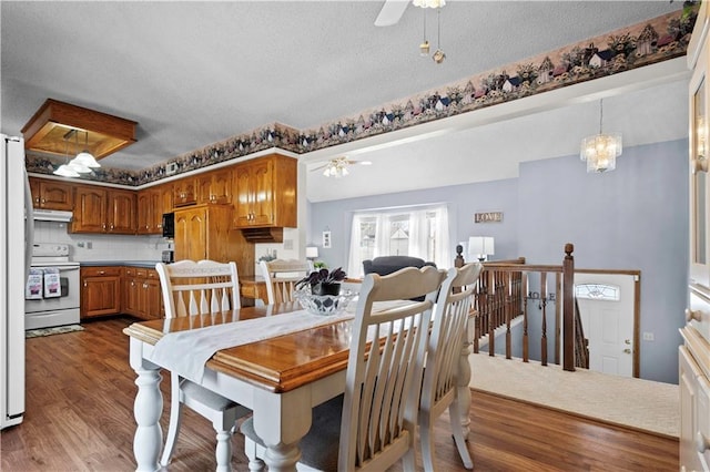 dining room with ceiling fan with notable chandelier, a textured ceiling, and wood finished floors