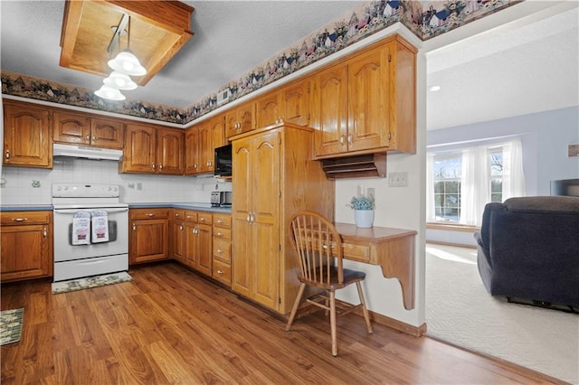 kitchen with black microwave, brown cabinetry, white range with electric stovetop, and under cabinet range hood