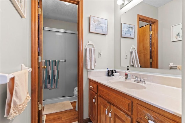 bathroom with a stall shower, toilet, a textured ceiling, and vanity