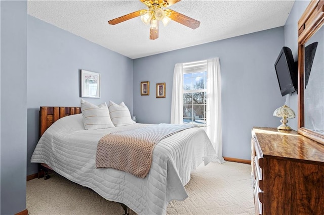 bedroom featuring a ceiling fan, baseboards, a textured ceiling, and light colored carpet