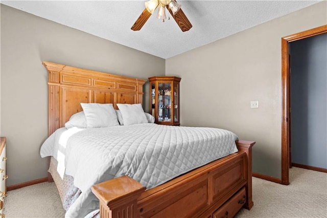 bedroom featuring light carpet, a textured ceiling, baseboards, and a ceiling fan