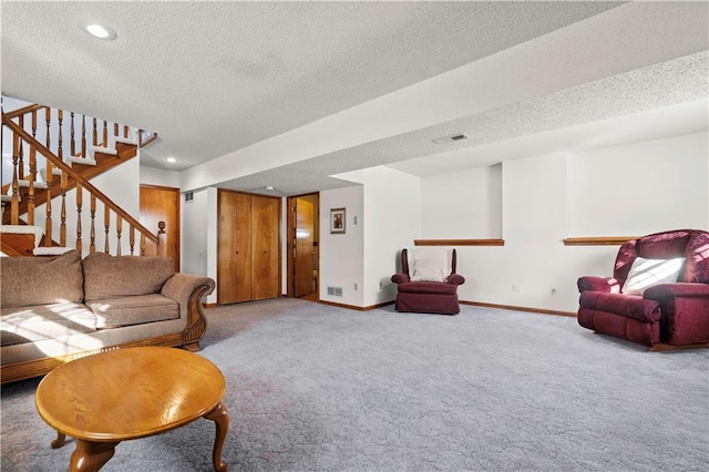 carpeted living room with a textured ceiling, recessed lighting, visible vents, baseboards, and stairs