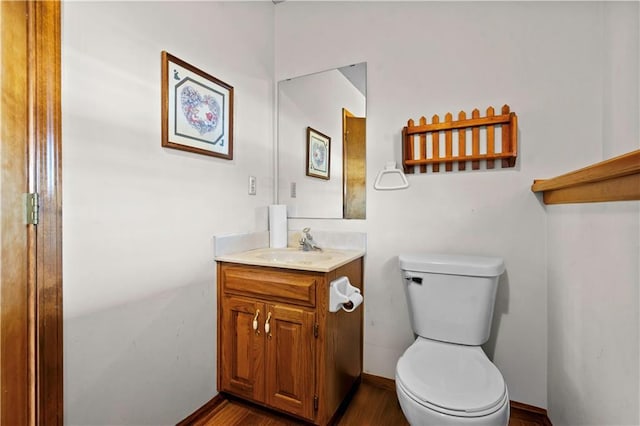 bathroom with baseboards, vanity, toilet, and wood finished floors