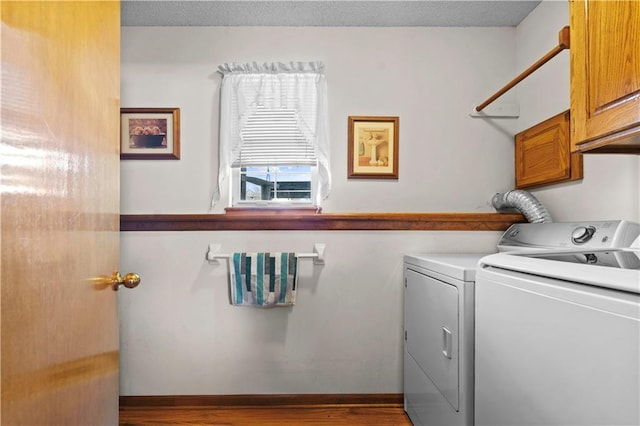 laundry area with cabinet space, light wood finished floors, and separate washer and dryer