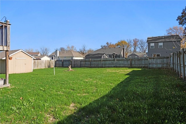 view of yard featuring a fenced backyard, a residential view, a storage unit, and an outdoor structure