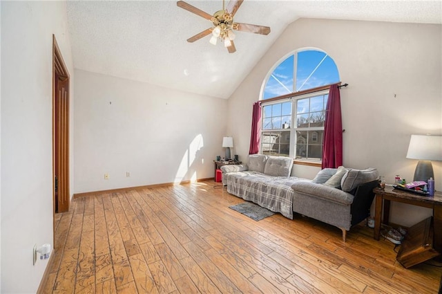 living area featuring high vaulted ceiling, light wood finished floors, baseboards, and a ceiling fan