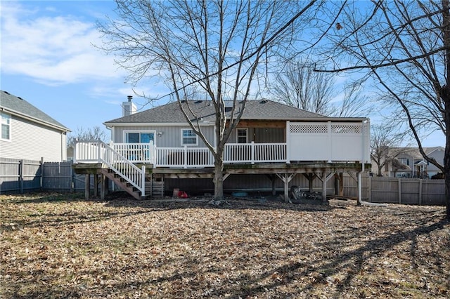 rear view of property featuring a shingled roof, a chimney, stairway, fence, and a deck