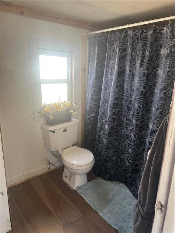 bathroom featuring toilet, a shower with curtain, baseboards, and wood finished floors