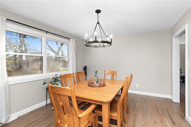 dining area featuring a notable chandelier, wood finished floors, and baseboards