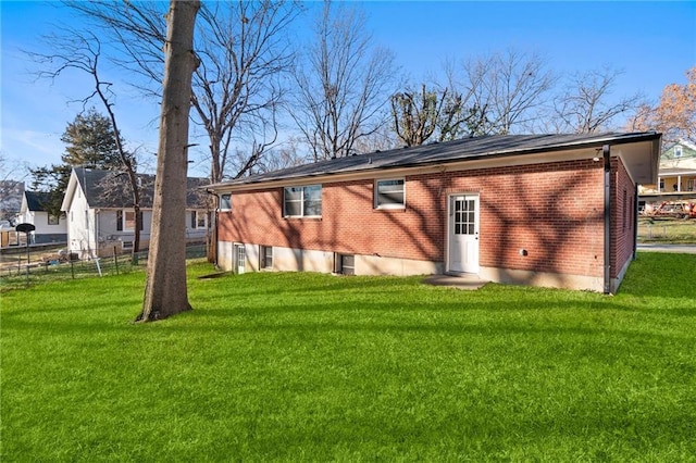 back of property with fence, a lawn, and brick siding