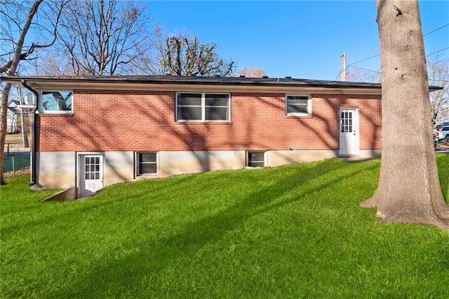 rear view of property featuring a yard and brick siding