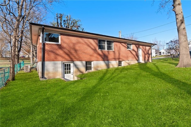 rear view of property featuring fence, a lawn, and brick siding