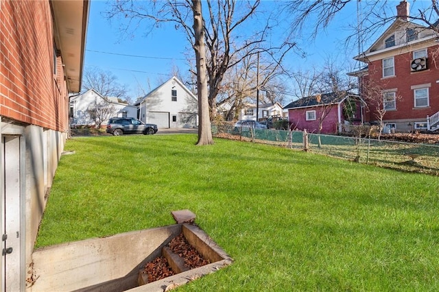 view of yard with a residential view, fence, and a detached garage