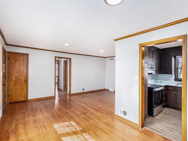 unfurnished living room with visible vents, light wood-style flooring, and baseboards