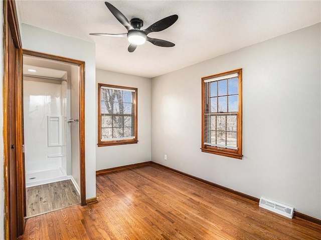 unfurnished bedroom featuring visible vents, baseboards, wood finished floors, and a ceiling fan