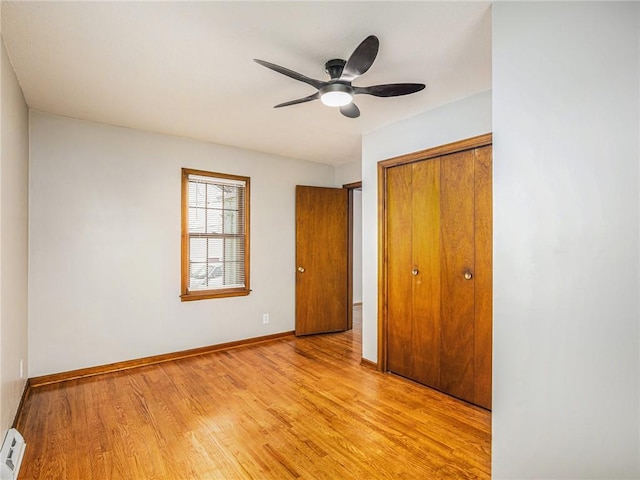 unfurnished bedroom with ceiling fan, baseboards, light wood-style floors, a closet, and a baseboard radiator