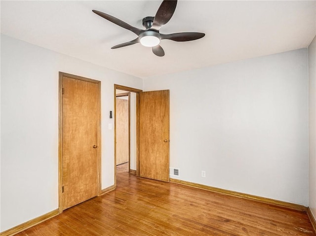 spare room with visible vents, ceiling fan, baseboards, and wood finished floors