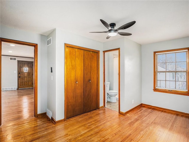 unfurnished bedroom with visible vents, baseboards, light wood-style floors, and a closet