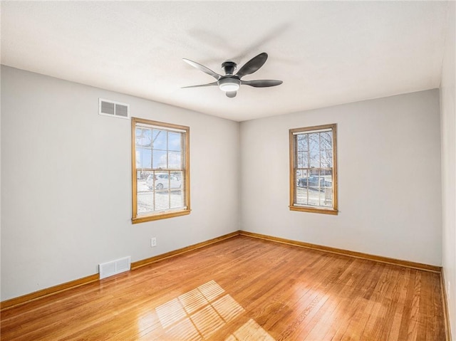 spare room with hardwood / wood-style flooring, baseboards, and visible vents