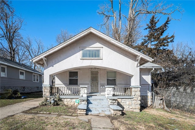 bungalow-style house with a porch, fence, and stucco siding