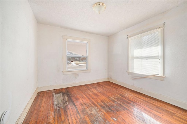 empty room featuring hardwood / wood-style flooring, baseboards, and a textured ceiling