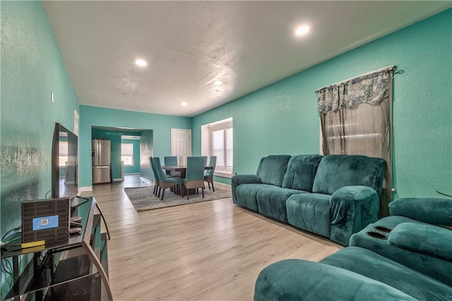 living room with recessed lighting, baseboards, wood finished floors, and a textured wall