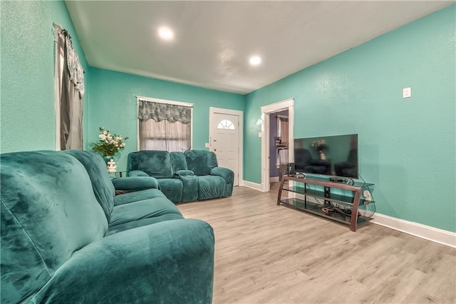 living area featuring baseboards and light wood finished floors