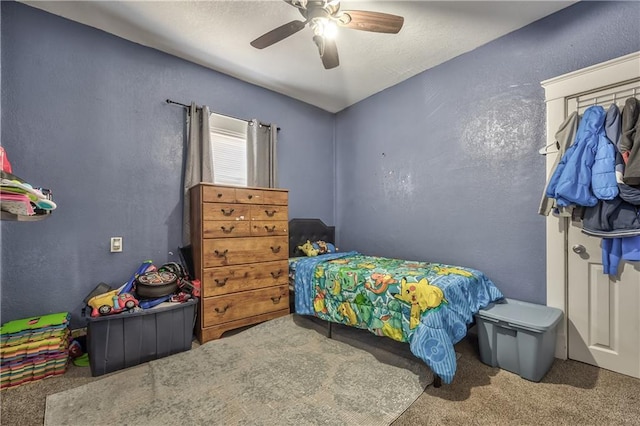 carpeted bedroom featuring a textured wall and a ceiling fan