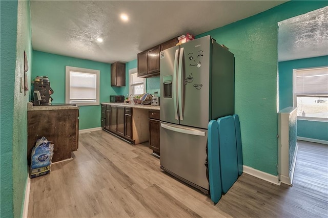 kitchen featuring baseboards, light countertops, stainless steel refrigerator with ice dispenser, and light wood-style floors