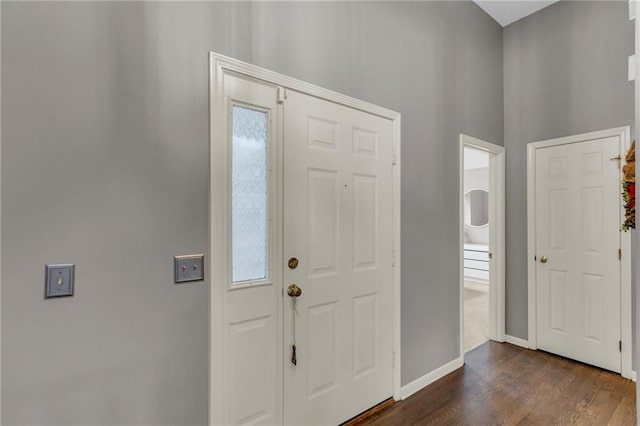 entrance foyer with a towering ceiling, baseboards, and dark wood finished floors