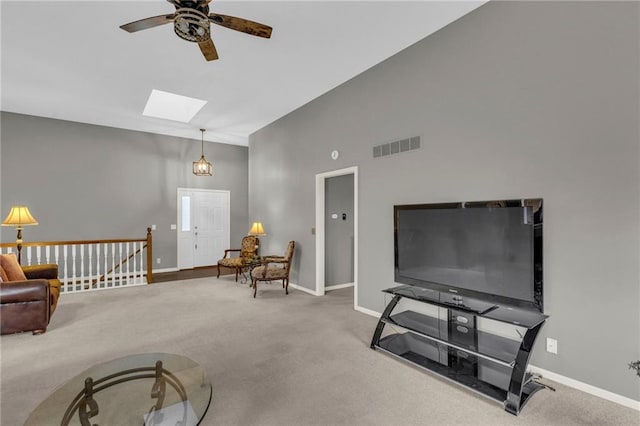 living room featuring carpet floors, a skylight, visible vents, and baseboards