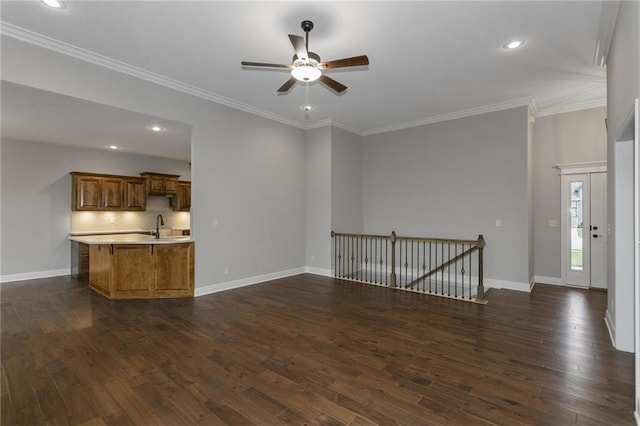 unfurnished living room featuring dark wood-style floors, ornamental molding, a sink, and baseboards